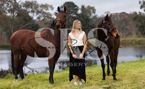 Woman standing with horses beside a lake