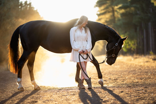 Woman walking with her horse during golden hour
